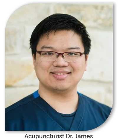 Acupuncturist Dr. James smiling in front of a stone wall.