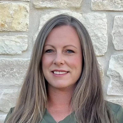 Nurse Practitioner Andrea Cristi Flynn smiling in front of a stone wall.